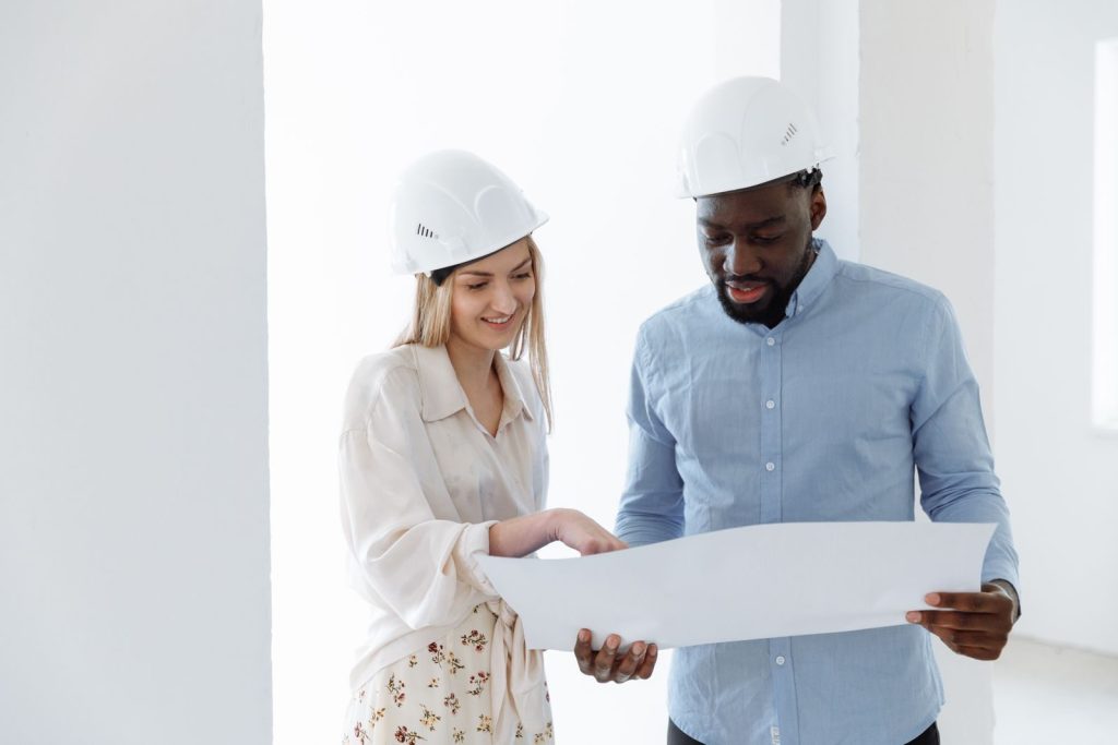 Two architects discussing a project with blueprints indoors.